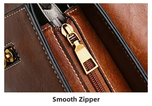 Macro shot of smooth bronze zipper and white contrast stitching on a brown leather handbag