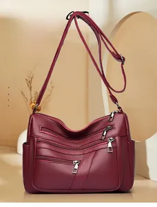 Detailed view of wine red crossbody bag with four zipper compartments and lychee texture