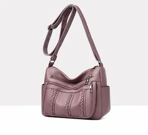Detalle de bolso morado oscuro con textura de litchi y múltiples bolsillos con cremallera