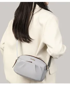 Close-up of a model wearing a light blue nylon crossbody bag with stylish pleat details
