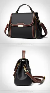 Detail of lychee textured black leather handbag with brown trim and gold side zippers