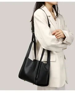 Detalle de bolso cubo en cuero granulado negro con pies metálicos dorados y logotipo