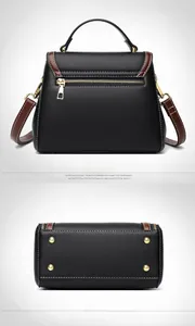 Detail of black pebbled leather handbag featuring back zipper pocket and metal base studs