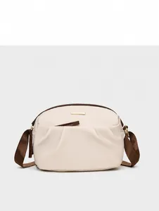 Front detail of beige nylon crossbody bag featuring pleated pockets and gold metal plaque