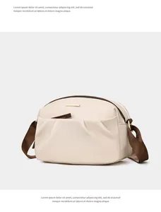 Detailed close-up of cream nylon crossbody bag with smooth texture and golden metal logo