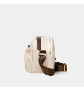 Detail view of beige crossbody bag showing side pleated pocket and brown nylon strap