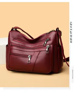 Detail view of burgundy soft leather texture and multi-pocket design on crossbody bag