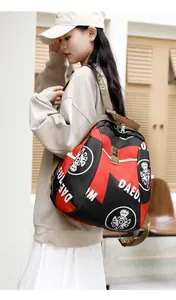 Détail d'un sac à dos décontracté rouge et noir avec logo DAEU et motif sourire sur modèle