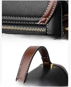 Close-up of black litchi grain leather bag with contrast brown handle and white stitching