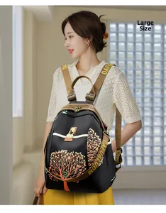 Detailed view of large black nylon backpack with orange tree patterns on female model