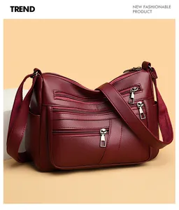 Detailed view of burgundy litchi grain leather crossbody bag with multiple front zip pockets