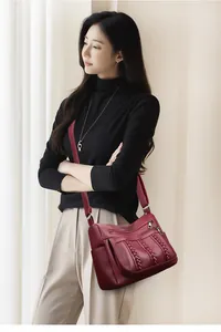 Detalle del bolso bandolera granate con cuero texturizado y bolsillos con cremallera