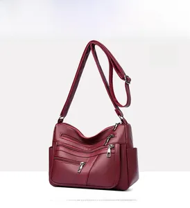 Detailed view of wine red leather bag showing multi-zipper pockets and silver hardware