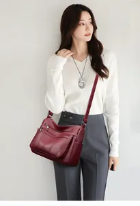 Detail of burgundy leather tote bag with three zippers shown on an elegant model