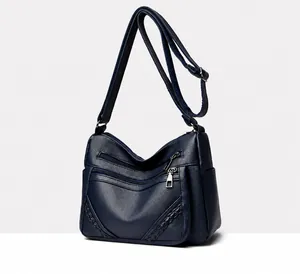 Detail van de blauwe crossbodytas van leer met meerdere zilveren ritsen en weefsels