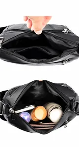 Detail showing the large main pocket and zipper bag of this black leather crossbody bag