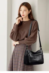 Detail of black soft leather crossbody bag showing multiple zip pockets and side pocket
