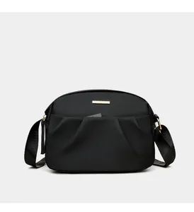 Detailed view of black nylon crossbody bag featuring gold hardware and pleated design