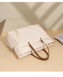 Detailed close-up of large laptop tote bag with gold zipper and brown handle accents