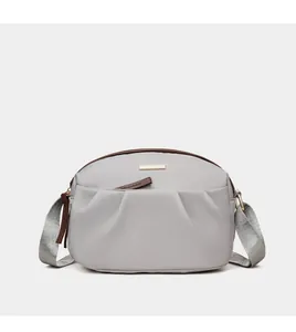 Detail of grey crossbody bag with pleated nylon fabric and golden metal logo plate