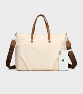 Detail of a beige laptop tote bag with brown straps and a phone for size reference