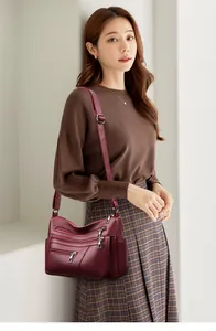 Detail view of wine red multi-zipper leather crossbody bag with adjustable strap