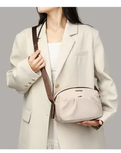 Close-up of beige crossbody bag with pleated detail and contrast brown shoulder strap