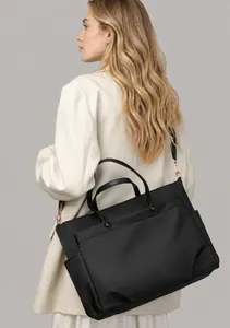 Side view of black nylon laptop tote bag shown on model with adjustable gold hardware