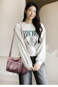 Bolso bandolera morado de cuero granulado con detalles trenzados mostrado en modelo