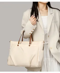 Detail of beige laptop tote bag with brown leather handles and gold snap pocket