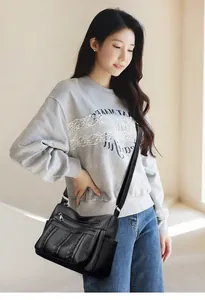 Detalle de bolso bandolera negro con textura de lichi y múltiples bolsillos con cremallera