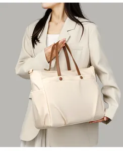 Detail view of cream laptop tote bag with brown handles and front buckle pocket