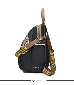 Detail view of black travel backpack with brown straps and floral pattern side pocket