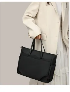 Detail of a black nylon laptop tote bag with faux leather handles and side pockets