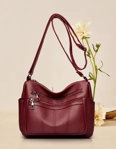 Detail view of burgundy leather crossbody bag with multiple zippers and large capacity