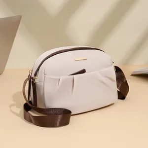 Minimalist beige waterproof nylon crossbody bag with brown strap and gold metal hardware
