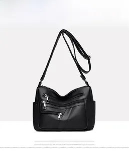 Front view of black pebbled leather crossbody bag with multiple zip pockets and strap