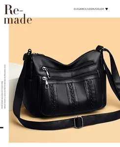 Detalle del bolso bandolera de cuero negro con líneas trenzadas y cremalleras plateadas