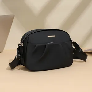 Fashionable black waterproof nylon crossbody bag with gold metal trim and pleated detail