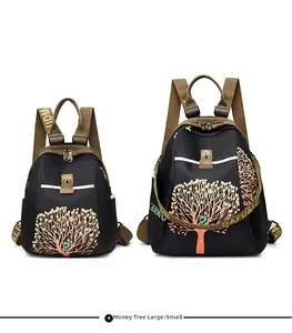 Size comparison of large and small black nylon backpacks with orange tree art and strap detail