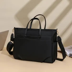 Fashionable black laptop tote bag for women with wide shoulder strap and gold hardware