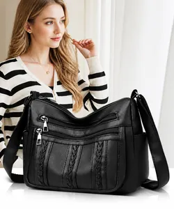 Detalle de bolso bandolera negro multibolsillos con cuero texturizado y adornos tejidos