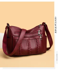 Detalle de bolso bandolera granate con cremalleras triples y diseño trenzado