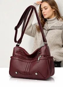Dettaglio borsa a tracolla in pelle bordeaux con cerniere multiple e fascia larga