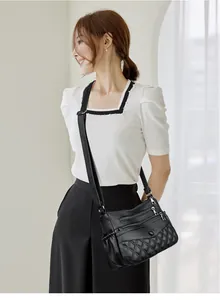 Détail d'un sac bandoulière noir en cuir matelassé avec plusieurs poches zippées