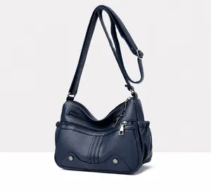Dettaglio della borsa a tracolla in pelle morbida blu scuro con trama litchi e tasche con zip