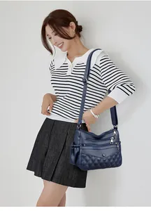 Sac bandoulière bleu foncé en cuir matelassé avec fermetures éclair sur le mannequin