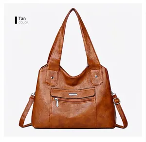 Detail view of yellow-brown soft leather tote bag with front zipper and silver hardware
