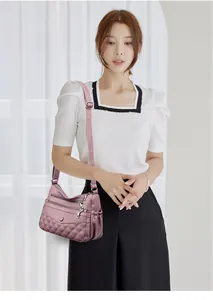 Détail du sac à bandoulière violet rose avec coutures matelassées et multiples poches zippées