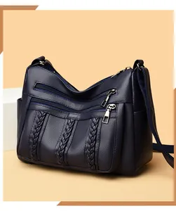 Detalle del bolso bandolera de cuero azul oscuro con rayas trenzadas y cremalleras de plata
